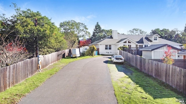 view of front of property featuring aphalt driveway, a chimney, and fence