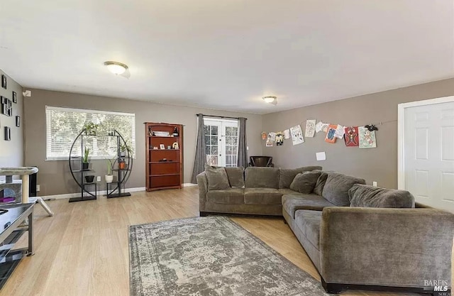 living area with a healthy amount of sunlight, light wood-type flooring, and baseboards