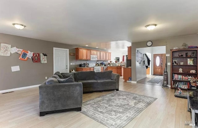 living room featuring visible vents, baseboards, and light wood-style floors