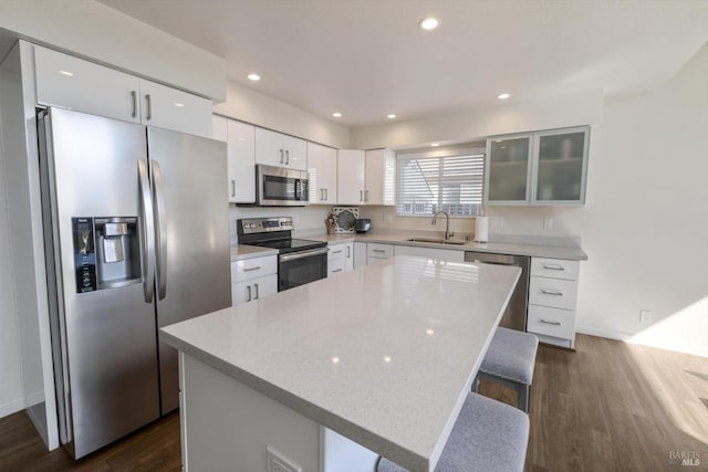 kitchen featuring dark wood-style floors, a sink, stainless steel appliances, white cabinets, and glass insert cabinets