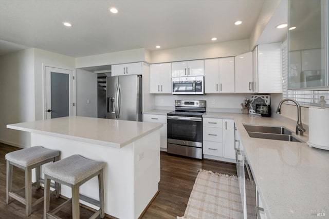 kitchen with dark wood-type flooring, a breakfast bar, recessed lighting, stainless steel appliances, and a sink