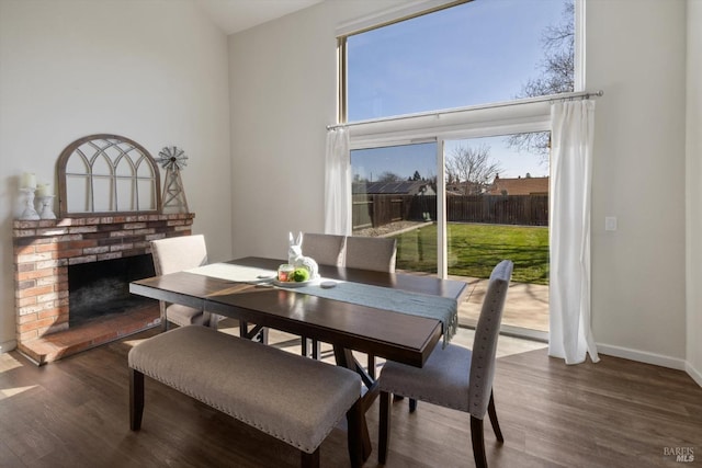 dining space with a fireplace, wood finished floors, and baseboards