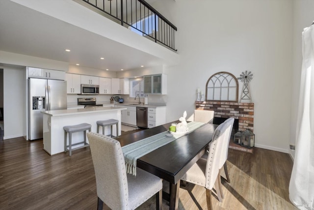 dining area with dark wood-style floors, recessed lighting, a high ceiling, and baseboards