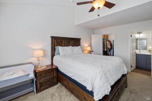 bedroom featuring a walk in closet, lofted ceiling, light carpet, ensuite bathroom, and a closet