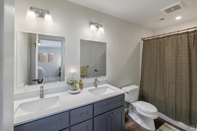 bathroom with double vanity, toilet, visible vents, and a sink