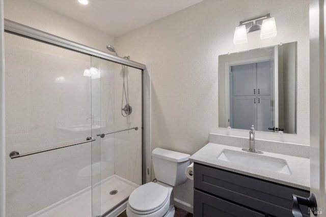 bathroom featuring a shower stall, toilet, vanity, and a textured wall