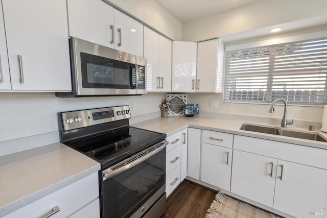 kitchen with a sink, appliances with stainless steel finishes, white cabinets, and light countertops