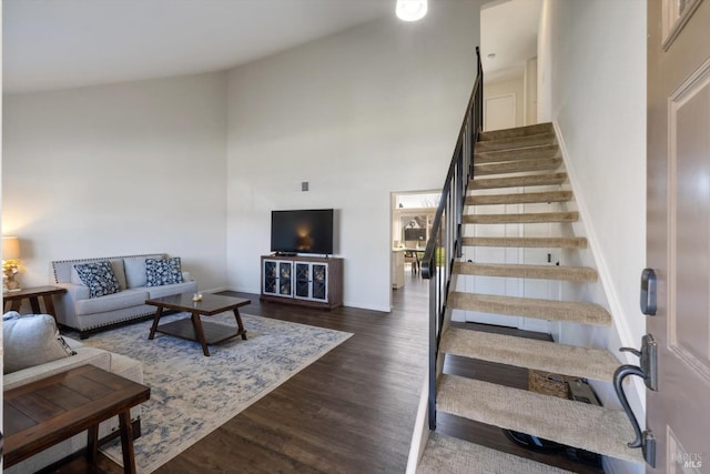 interior space featuring a high ceiling, baseboards, and wood finished floors