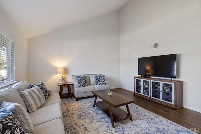 living room with lofted ceiling, wood finished floors, baseboards, and visible vents