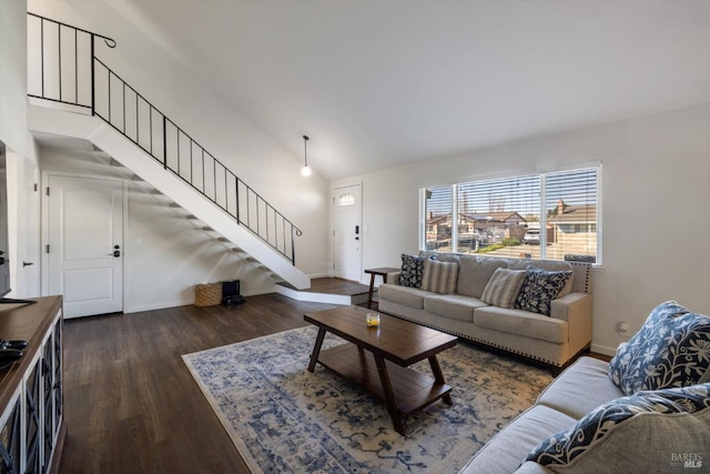 living area with vaulted ceiling, stairs, baseboards, and wood finished floors