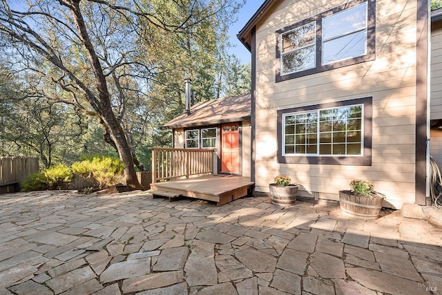 rear view of property featuring a wooden deck, a patio, and fence