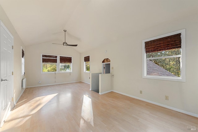 spare room with lofted ceiling, radiator heating unit, light wood-style floors, baseboards, and ceiling fan