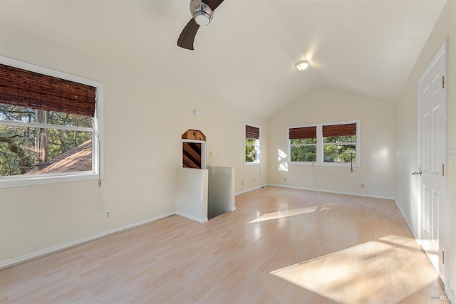 empty room with baseboards, light wood-style floors, ceiling fan, and vaulted ceiling