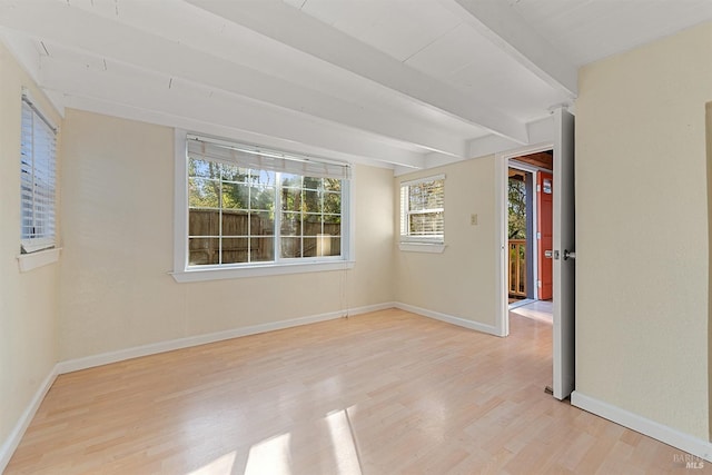 empty room featuring beam ceiling, light wood-style flooring, and baseboards