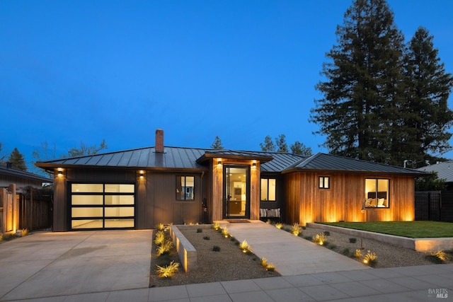 view of front of property featuring a standing seam roof, metal roof, driveway, and fence