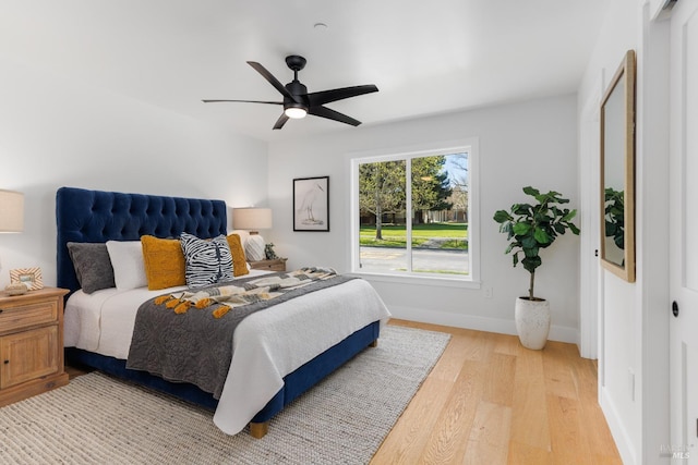 bedroom featuring light wood-type flooring, baseboards, and a ceiling fan