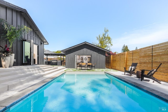 view of swimming pool featuring an outbuilding, fence, a fenced in pool, and a patio area