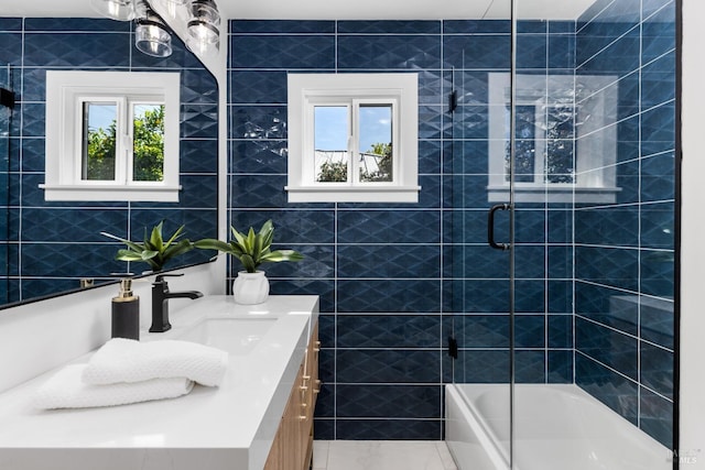 full bath featuring combined bath / shower with glass door, vanity, and tile walls