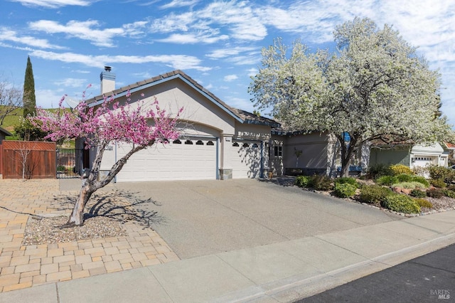 ranch-style house with fence, stucco siding, a chimney, driveway, and an attached garage