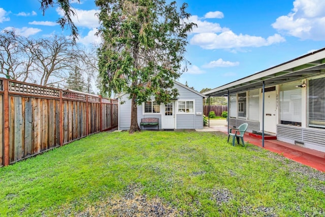 view of yard with an outbuilding, a fenced backyard, and a patio