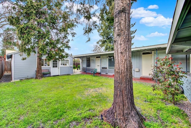 back of property with a yard, an outbuilding, and fence