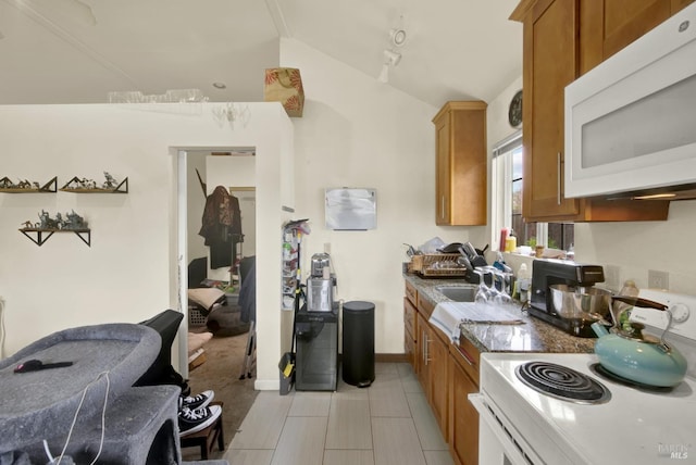 kitchen featuring a sink, white appliances, lofted ceiling, and brown cabinets