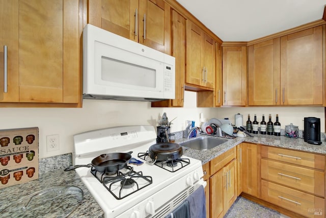 kitchen featuring brown cabinetry, white appliances, light stone countertops, and a sink