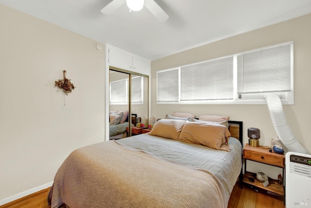 bedroom featuring a closet, ceiling fan, baseboards, and wood finished floors