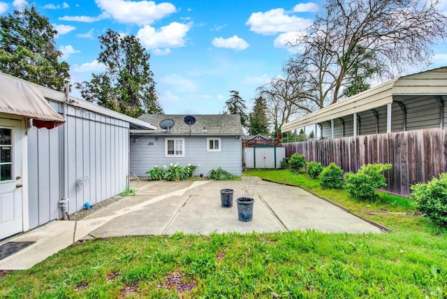 rear view of house featuring an outbuilding, a shed, fence, a yard, and a patio area