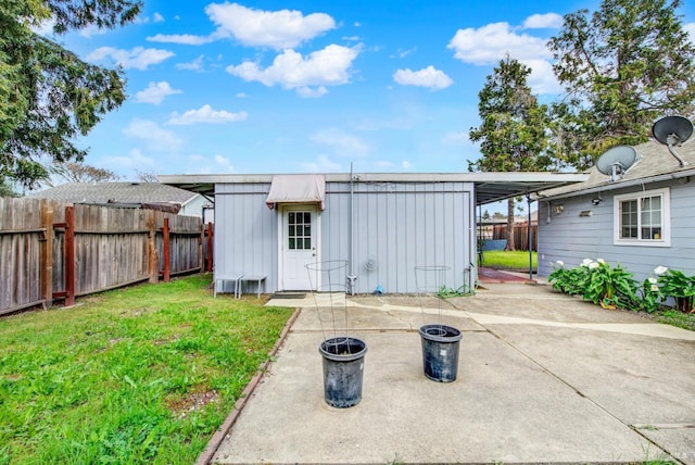 back of property with a yard, an attached carport, board and batten siding, and a fenced backyard