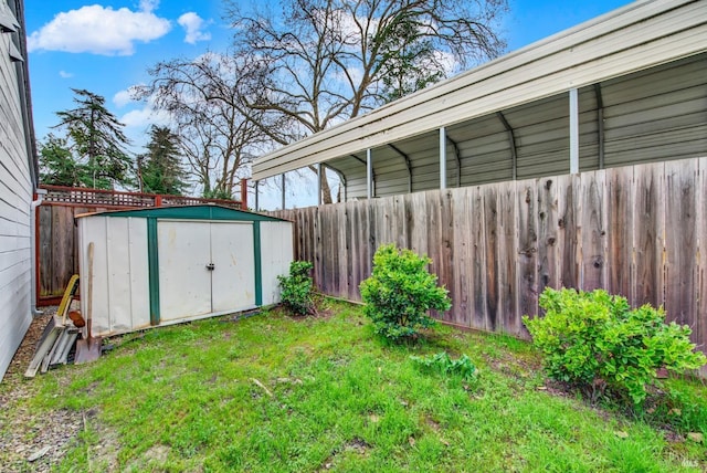 view of yard featuring a detached carport, an outbuilding, fence, and a shed