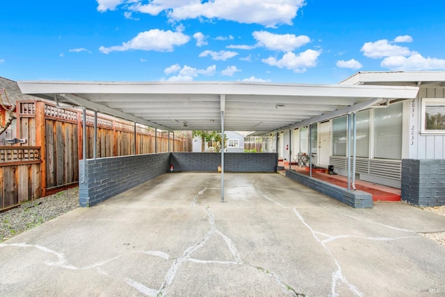 view of patio / terrace featuring a carport, concrete driveway, and fence