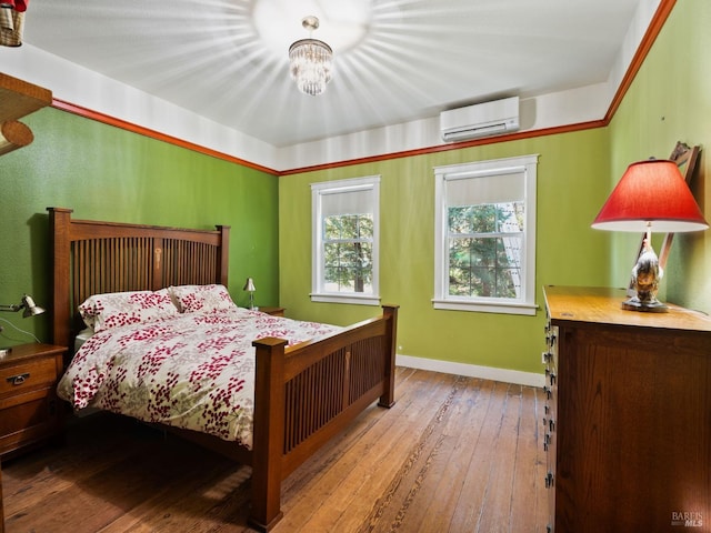 bedroom with a wall mounted air conditioner, baseboards, and wood-type flooring