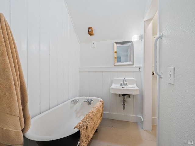 bathroom with a sink, a freestanding tub, and wainscoting