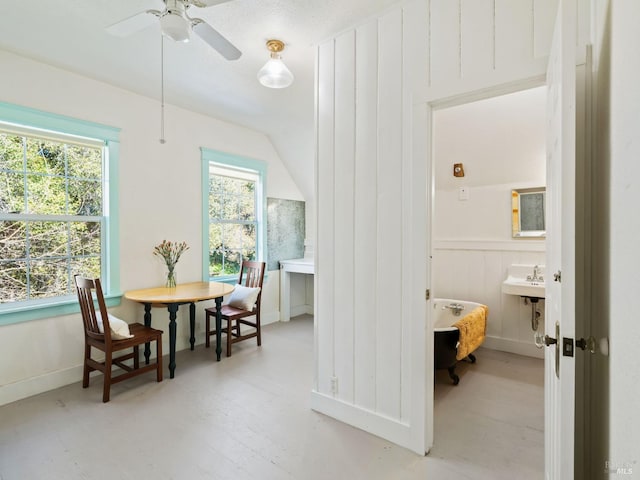 interior space featuring lofted ceiling, wainscoting, and a ceiling fan