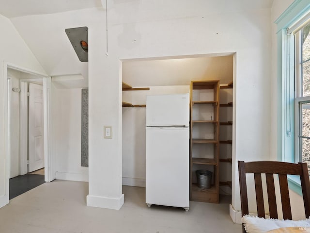 bedroom featuring finished concrete flooring and freestanding refrigerator