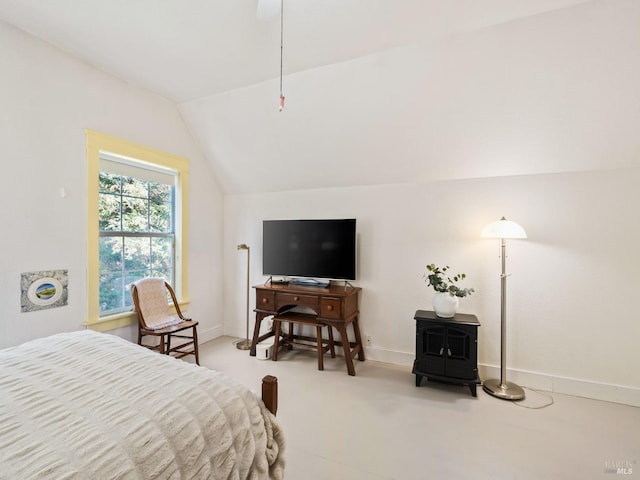 bedroom featuring vaulted ceiling, a wood stove, and baseboards