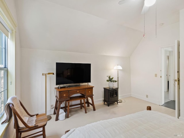 bedroom with baseboards, ceiling fan, a wood stove, and vaulted ceiling