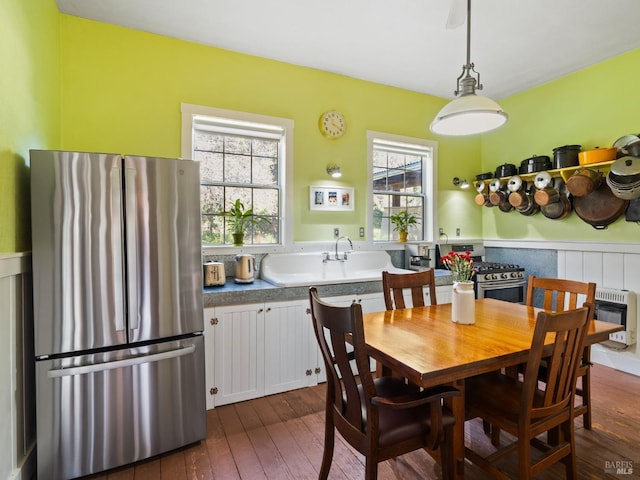 dining room featuring heating unit, a healthy amount of sunlight, and dark wood-style flooring