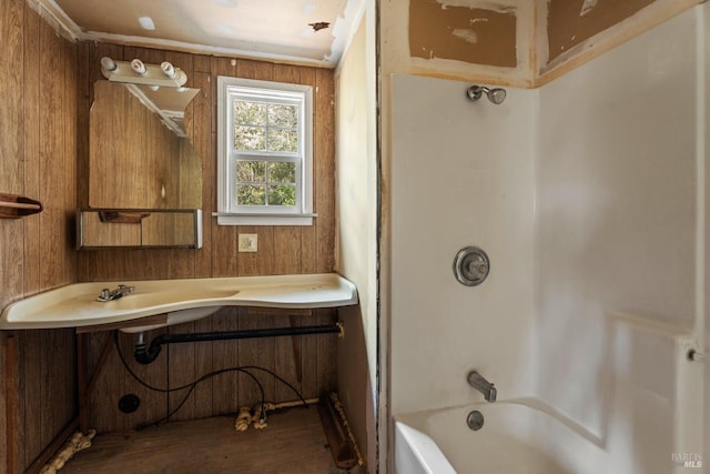 bathroom featuring vanity, wooden walls, and tub / shower combination