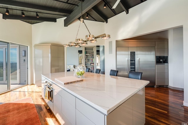 kitchen with dark wood-style floors, an inviting chandelier, appliances with stainless steel finishes, beamed ceiling, and modern cabinets