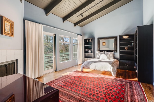 bedroom with wood ceiling, beam ceiling, a fireplace, wood finished floors, and access to outside