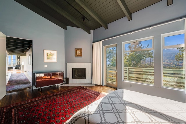 bedroom featuring a tiled fireplace, wood ceiling, beam ceiling, wood finished floors, and high vaulted ceiling