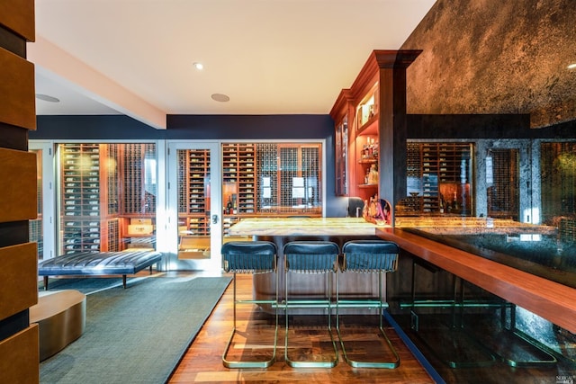 bar with indoor wet bar, beamed ceiling, and wood finished floors