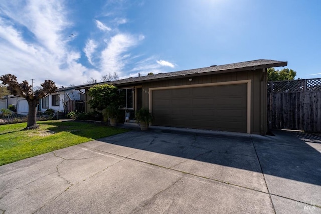 ranch-style home featuring a front yard, concrete driveway, fence, and an attached garage