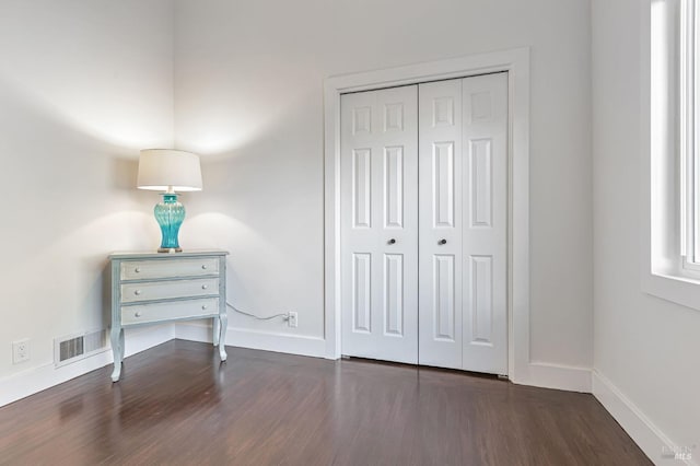 bedroom with baseboards, visible vents, and wood finished floors
