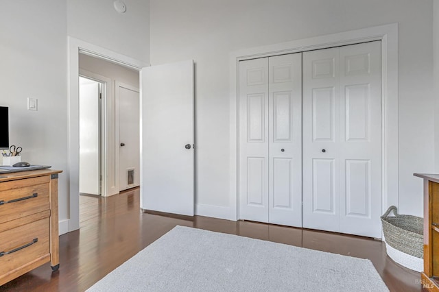 bedroom with dark wood-style floors, a closet, and baseboards