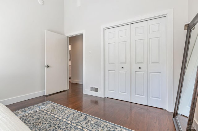 unfurnished bedroom featuring a closet, baseboards, visible vents, and dark wood-style flooring