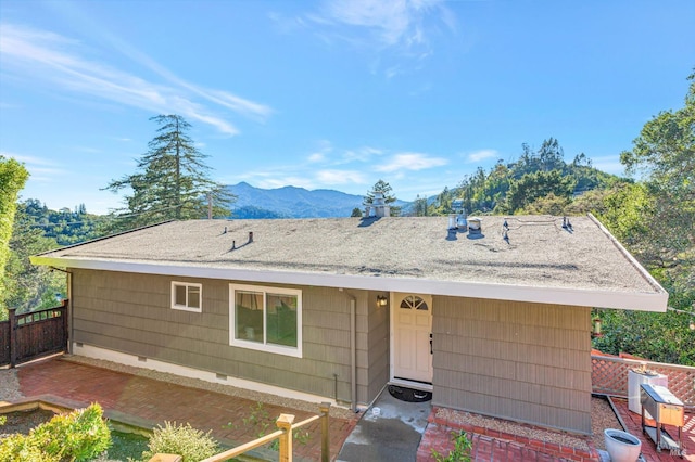 view of front of property with fence, roof with shingles, crawl space, a mountain view, and a patio