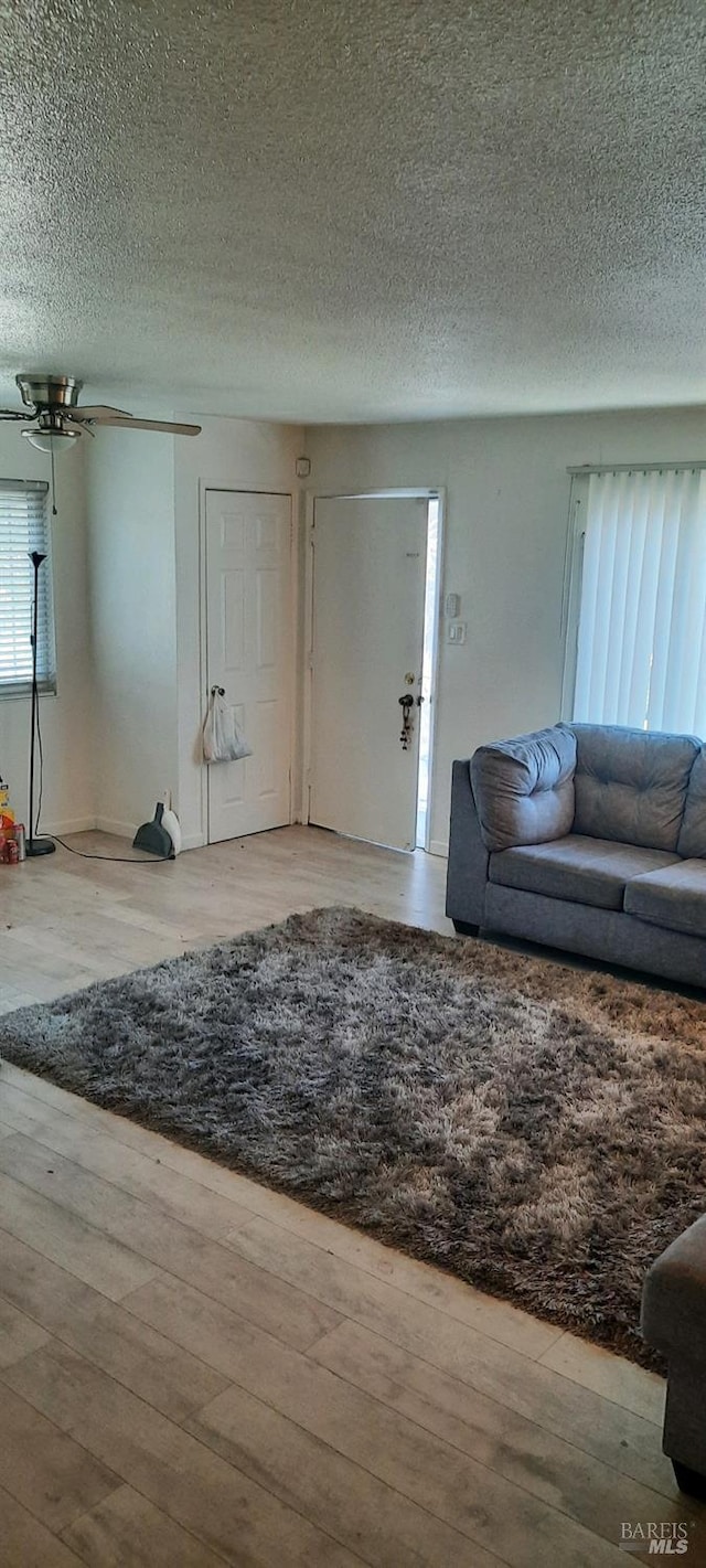 unfurnished living room with a textured ceiling and wood finished floors